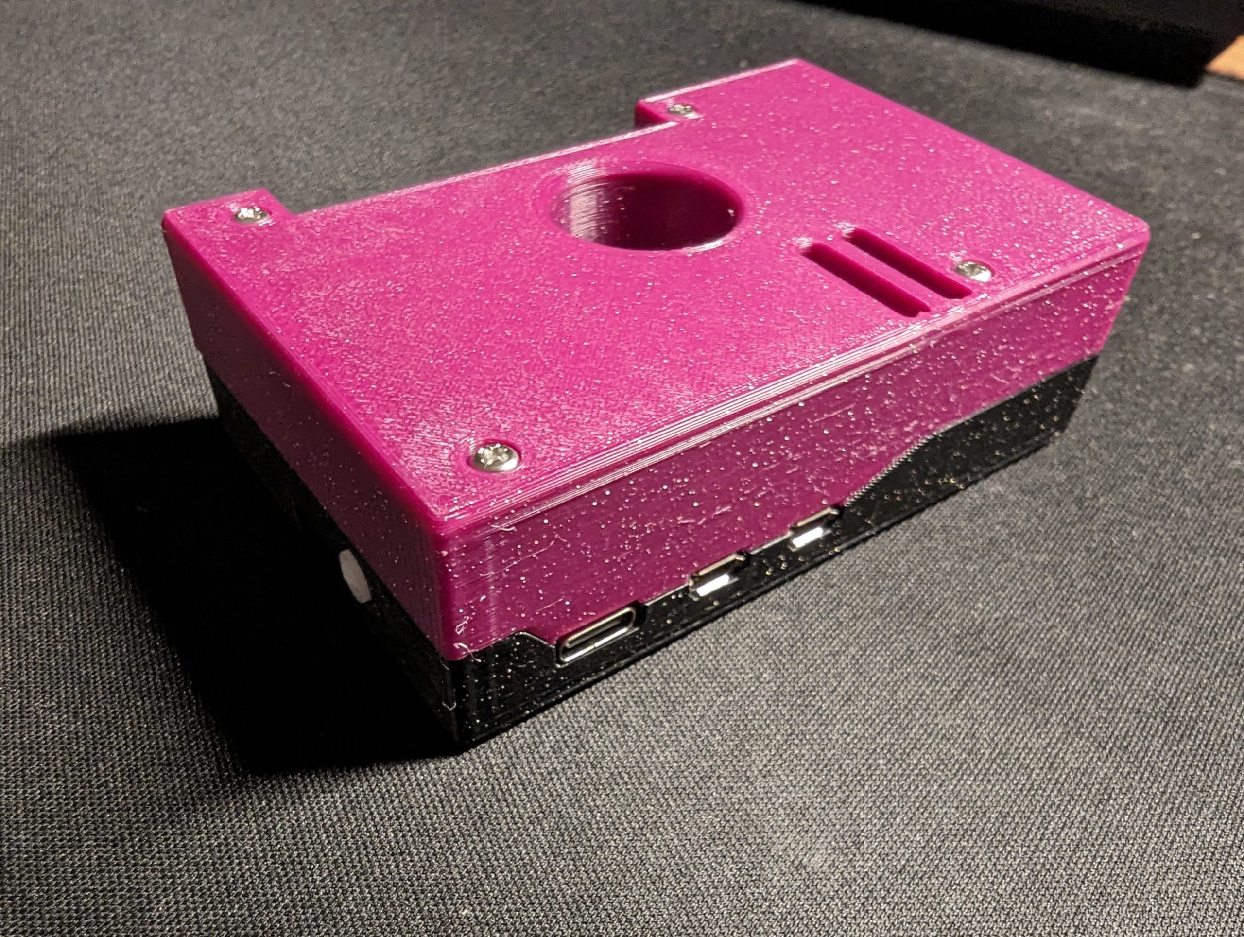The assembled Raspberry Pi 5 case, with the top part printed in purple and the bottom part black.